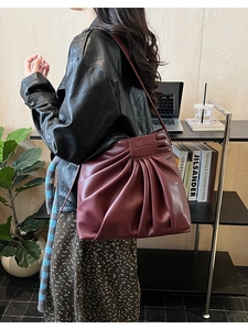 Detail of burgundy pleated tote bag showing the embossed logo and soft faux leather texture