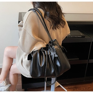 Detail of black drawstring bucket bag with leather star charm and smooth finish