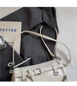 Detailed macro view of matte cream PU leather shoulder bag with buckle and D-ring