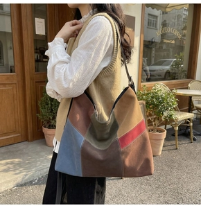 Retro patchwork suede tote bag shown on shoulder in a stylish outdoor cafe setting