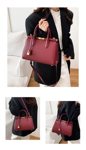 Detail of burgundy leather handbag with gold padlock charm and detachable shoulder strap