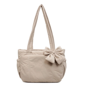 Puffy beige quilted tote bag featuring a large decorative bow and side pockets