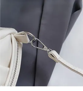 Detailed close-up of silver metal hooks and D-ring on cream pleated shoulder bag