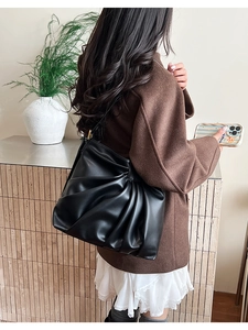 Close-up of black pleated tote bag made of glossy PU leather for commuter outfits