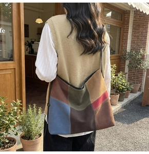 Detail of multi-color patchwork suede tote bag worn on shoulder in outdoor cafe