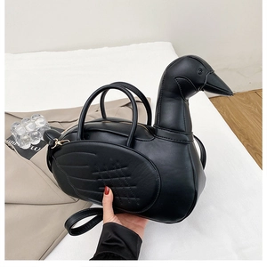 Détail du sac à main noir en forme d'oie montrant le cuir mat et la broderie