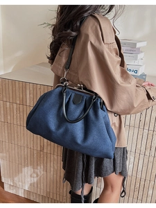 Détail latéral d'un sac docteur en denim bleu foncé avec poignées en cuir noir et finitions argent