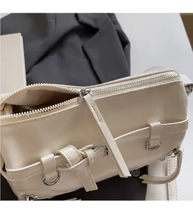 Detail of smooth silver zipper and decorative side straps on cream PU leather pillow bag