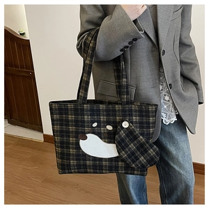Vista dettagliata della borsa tote a quadri marroni con toppa a forma di cane e ciondolo