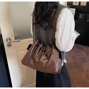 Close-up of deep brown drawstring bucket bag with star pendant on model