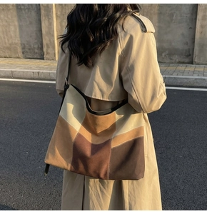 Detail view of large patchwork suede tote bag worn by a model in urban setting