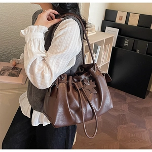 Detail of dark brown drawstring tote bag with star charm and glossy leather texture