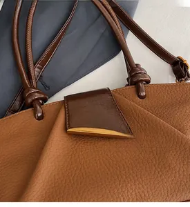 Detail of lychee pattern leather handbag with knotted handle and golden buckle