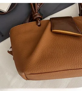 Detailed macro view of the knot handle and gold buckle on a brown leather handbag