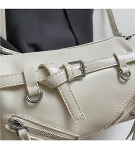 Close-up of cream white faux leather bag featuring a buckle and metal zipper detail