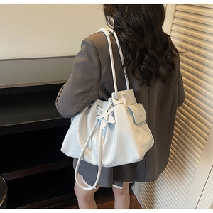 White drawstring bucket bag with pleated edge and star charm shown on shoulder