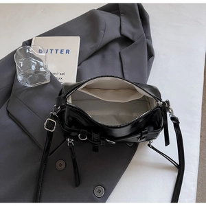 Detail of glossy black leather crossbody bag interior showing silver zipper and white lining