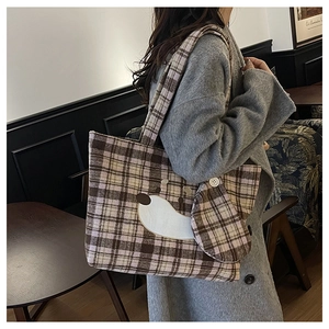 Dettaglio di una borsa tote a quadri marroni con ricamo a cane e mini pochette coordinata