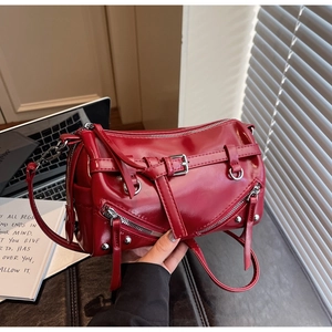 Detail of burgundy glossy PU leather bag with decorative buckles and metal zippers