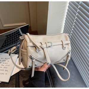 Detail view of cream-colored pillow bag with decorative buckles and metal zippers