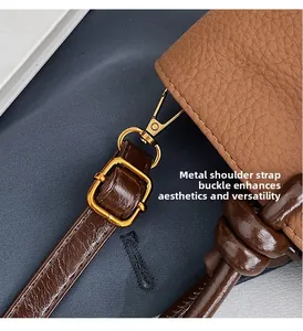 Detailed close-up of golden metal buckle and brown leather strap on pebble grain bag