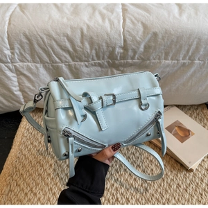 Detail of light blue motorcycle style pillow bag with silver rivets and zippers