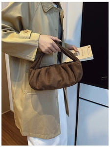 Detail of dark brown ruched cloud bag in faux suede fabric with elegant knot handle detail