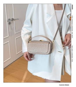 Model showcasing a champagne sequin box bag with gold lock and thin shoulder strap