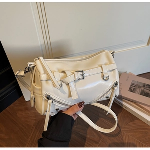 Detail of cream Y2K crossbody bag featuring silver rivets and decorative side zippers