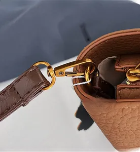 Detail view of gold hardware hook on brown lychee grain leather shoulder bag