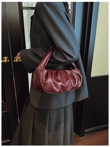 Close-up of pleated burgundy cloud bag showing glossy faux leather texture and soft folds
