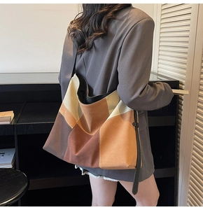 Detailed view of color-block patchwork tote bag in earth tones with sleek shoulder strap