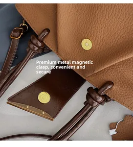 Detail of the high-quality magnetic closure and litchi grain leather on the brown handbag