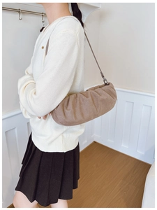 Detail of a brown pleated cloud bag in matte faux suede with slim straps and metal hooks