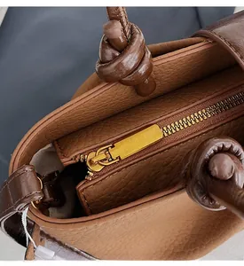 Detail of golden zipper and brown lychee grain leather with a creative knotted handle