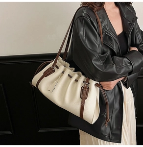 Detail of cream pleated tote bag with brown leather straps shown on a model