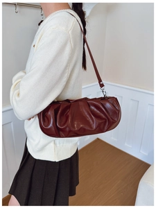 Detail of burgundy ruched cloud bag showing glossy leather texture and stylish shoulder strap