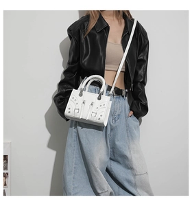 Close-up of a white leather motorcycle bag with silver rivets and zippers on a model