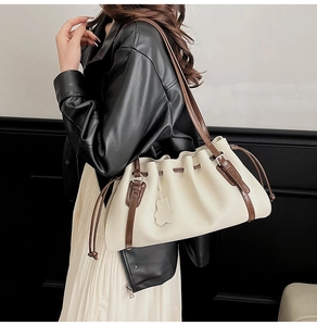 Detail view of cream leather tote bag with brown straps and cute bear charm decoration