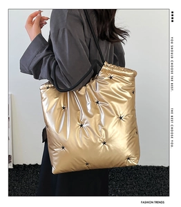 Detail of metallic gold quilted tote bag with black star embroidery and sleek drawstrings