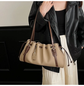 Detailed view of the khaki pleated hobo bag with dark brown handles on model shoulder