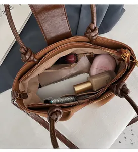 Top-down view of a brown leather bag showing spacious interior with cosmetics and pockets