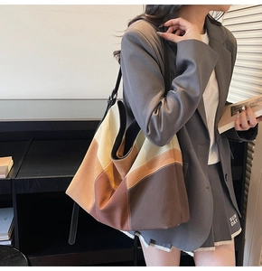 Detail view of large color-block tote bag in brown and beige on a female model