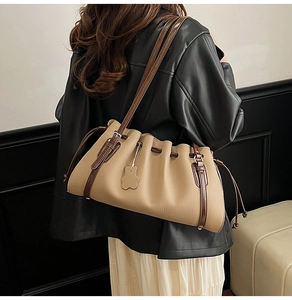 Detail of khaki leather bucket bag featuring drawstring closure and petal shaped charm