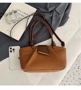 Detailed comparison showing brown pleated shoulder bag size next to an iPhone