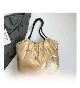 Detail view of gold quilted star tote bag with black rope handles and embroidery