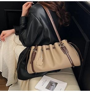 Detail of grey bucket bag with drawstring closure and brown leather straps on a model