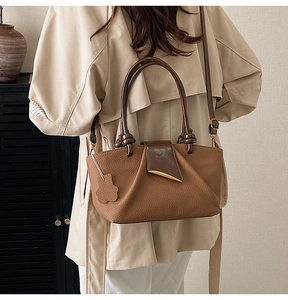 Detailed view of brown litchi leather bag featuring pleated texture and metal clasp