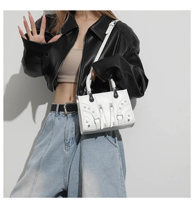 Detail of white leather motorcycle bag with silver rivets and zippers on a model