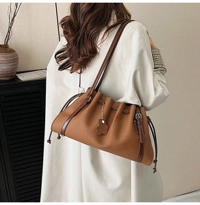 Detail of dark brown leather bucket bag with drawstring closure and cute bear charm